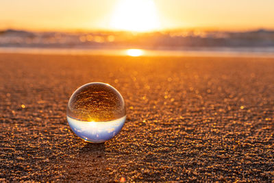 Close-up of crystal ball on water against sky during sunset