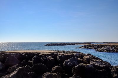 Scenic view of rocky shore and sea against sky