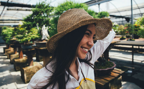 Close-up of young woman wearing hat in greenhouse