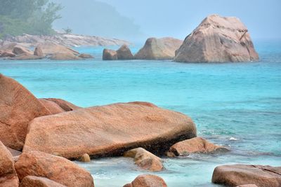 Rocks on shore by sea against sky