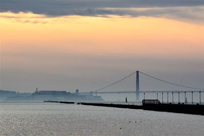 View of suspension bridge over sea during sunset