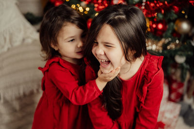 Portrait of young woman standing against christmas tree