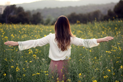 Rear view of woman with arms raised on field