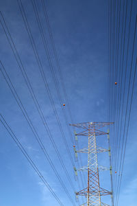 Low angle view of electricity pylon against blue sky