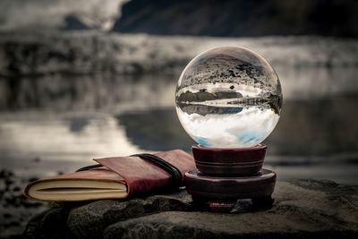Close-up of crystal ball with reflection by book on rock