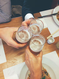 High angle view of men toasting beer at table