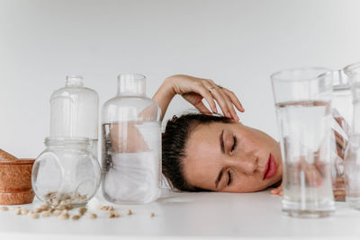 Close-up of woman holding bottle against white background