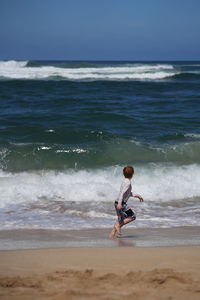 Young boy running with the waves on the beach in hawaii. 