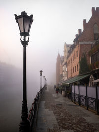 Street light on footpath amidst buildings in city