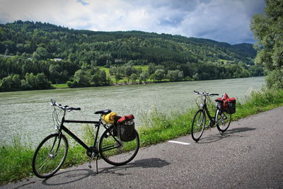 Bicycle on road by river against sky