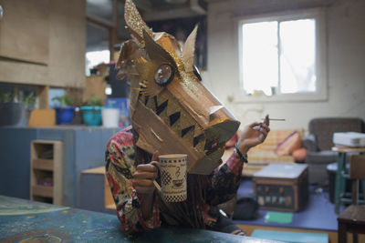 Portrait of young female artist wearing a dragon mask