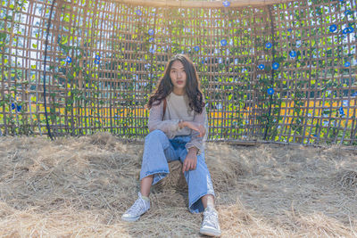 Full length portrait of woman sitting against plants