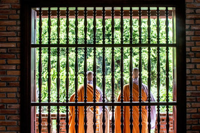 Rear view of monks seen through window at pagoda