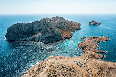 Rock formations on shore by sea against sky