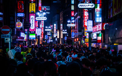 Crowd amidst illuminated billboards on buildings in city