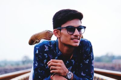 Young man wearing sunglasses standing against clear sky