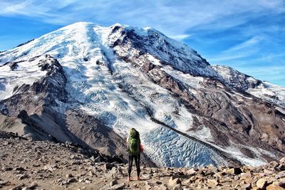 Rear view of woman standing on field against snow covered mountain