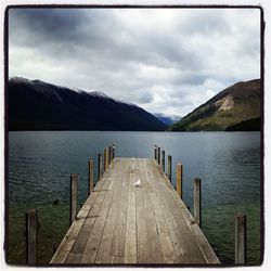 Pier on lake against cloudy sky