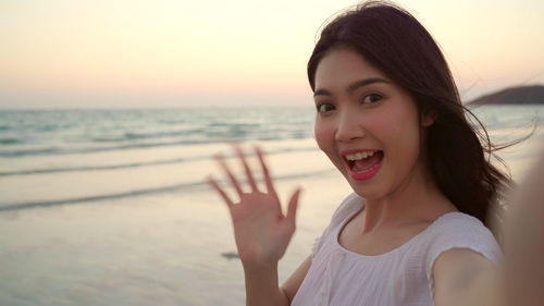 Portrait of smiling young woman on beach during sunset