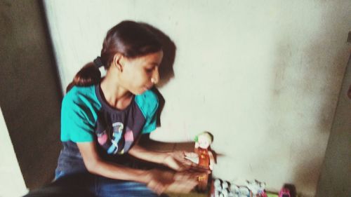 Boy looking away while sitting on wall at home