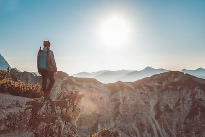 Rear view of a woman standing on mountain against sky