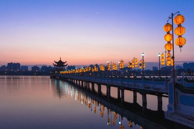 Decorated bridge over river leading towards temple against clear sky