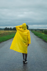 Rear view of woman with umbrella walking on road