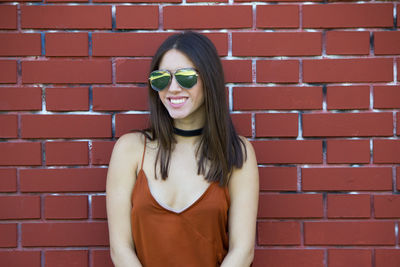 Portrait of smiling woman standing against brick wall