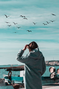 Rear view of woman with seagulls flying over sea