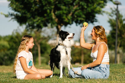 Rear view of woman with dog sitting on field