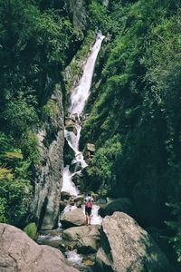 Rear view of woman standing on rock by river