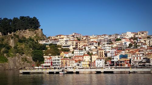 Buildings by sea against clear sky