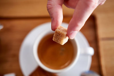 Close-up of hand holding coffee cup on table