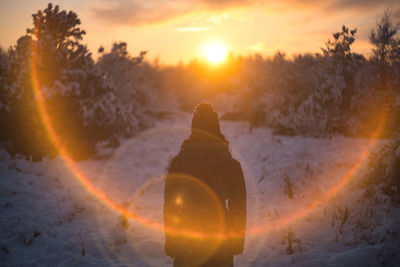 Cropped hand of woman holding crystal against sky during sunset
