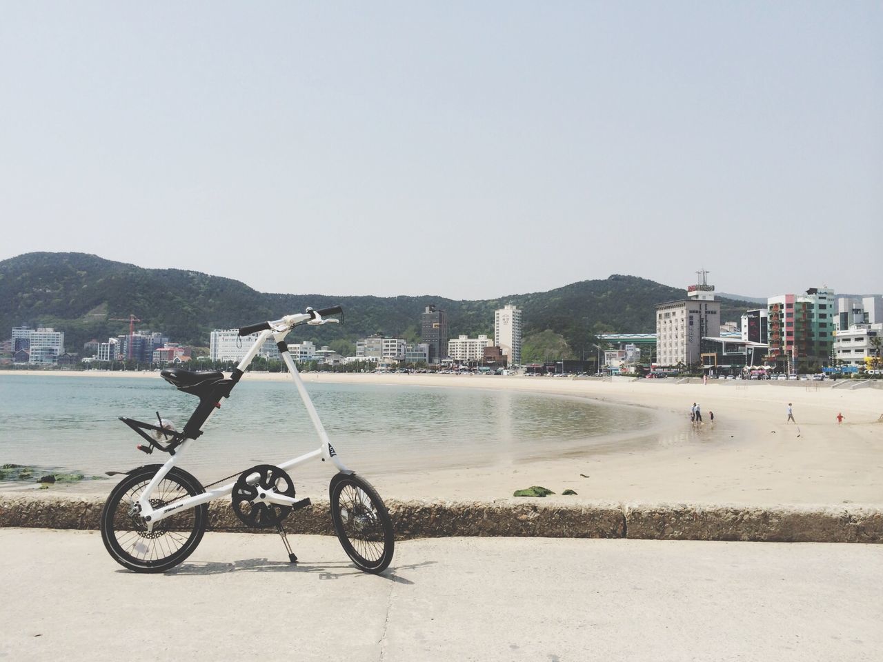 bicycle, transportation, mode of transport, clear sky, building exterior, water, architecture, copy space, built structure, land vehicle, parking, parked, city, beach, sea, stationary, day, nautical vessel, outdoors, incidental people