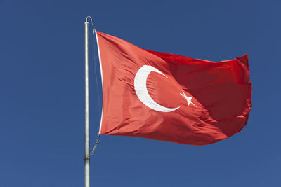 Low angle view of flag against blue sky