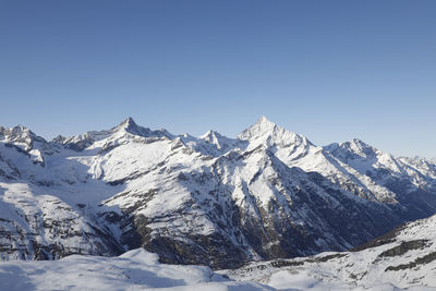 Scenic view of snowcapped mountains against clear sky