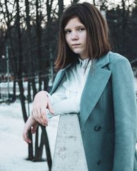 Portrait of beautiful young woman standing against trees