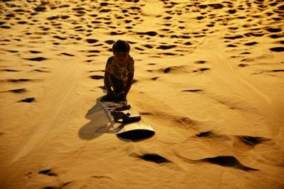 High angle view of boy sandboarding in desert