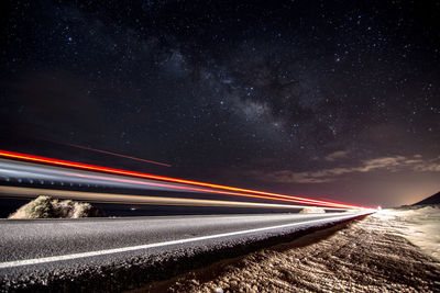 Light trails on road against sky at night