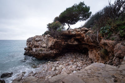 Rock formation on beach against sky