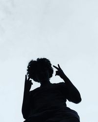 Low angle view of silhouette person holding cigarette against sky