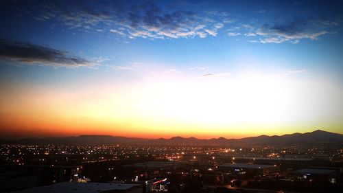 High angle view of illuminated city against sky at sunset