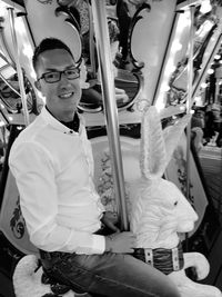 Full length portrait of man holding eyeglasses in bus