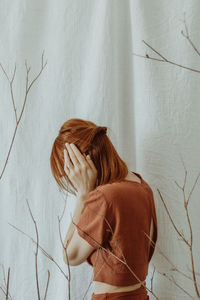 Rear view of woman standing against wall