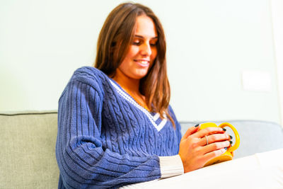 Smiling young woman sitting at home