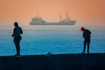 Rear view of man and woman standing by sea against sky