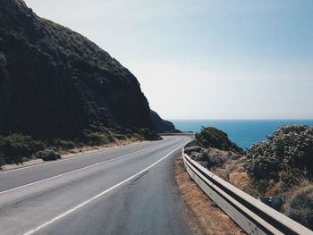 Scenic view of road by sea against sky