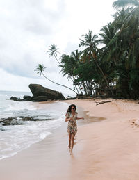 Woman running at beach against sky