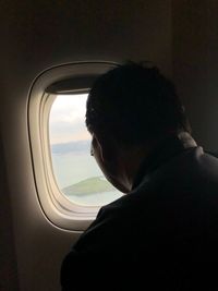 Portrait of man looking through airplane window